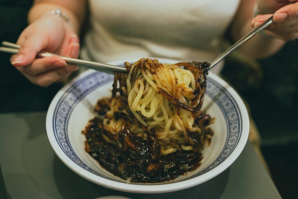 “Bowl of Korean jjajangmyeon noodles topped with rich black bean sauce, vegetables, and sliced meat.”