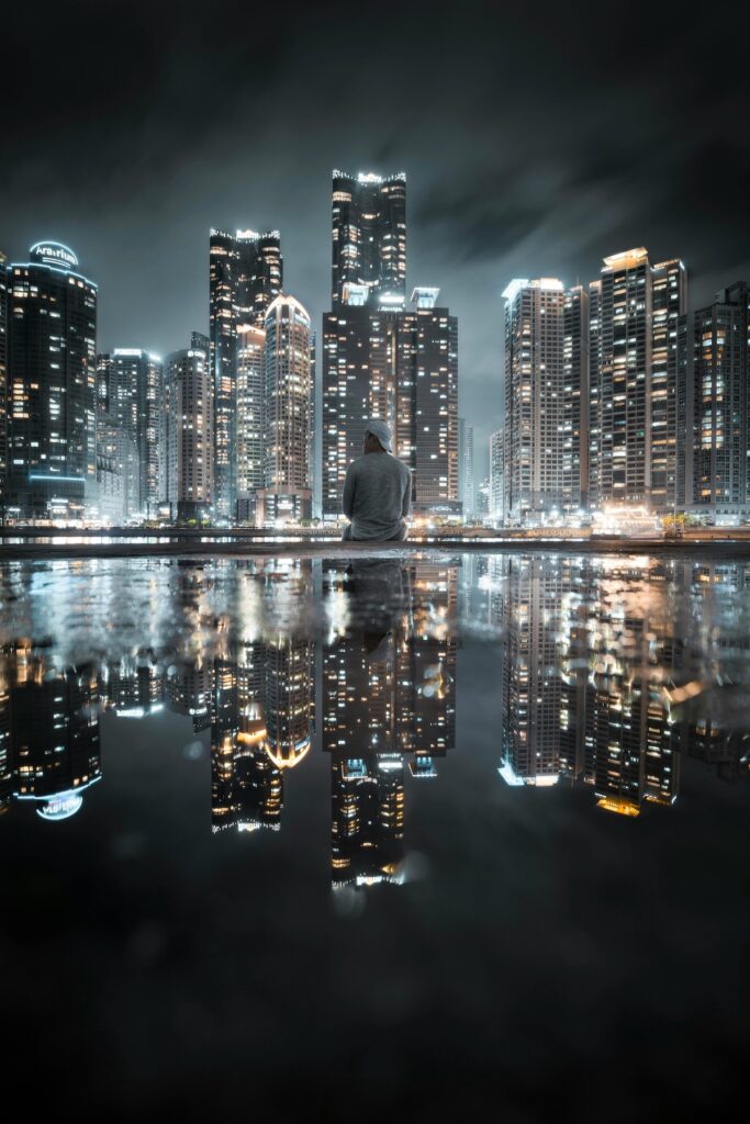 "Night view of Busan with Gwangandaegyo Bridge illuminated over the ocean, surrounded by city lights and high-rise buildings."