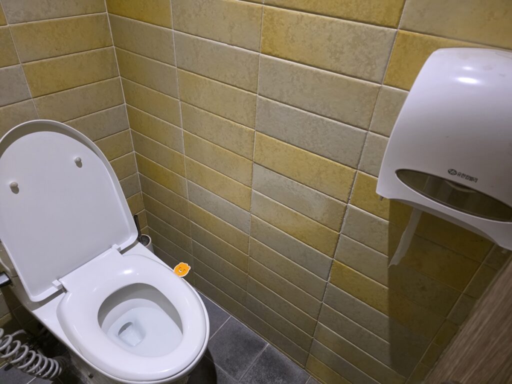 A clean toilet equipped with a bidet and a fully stocked tissue dispenser in Korean restaurant bathrooms. A clean toilet equipped with a bidet and a fully stocked tissue dispenser in Korean restaurant bathrooms