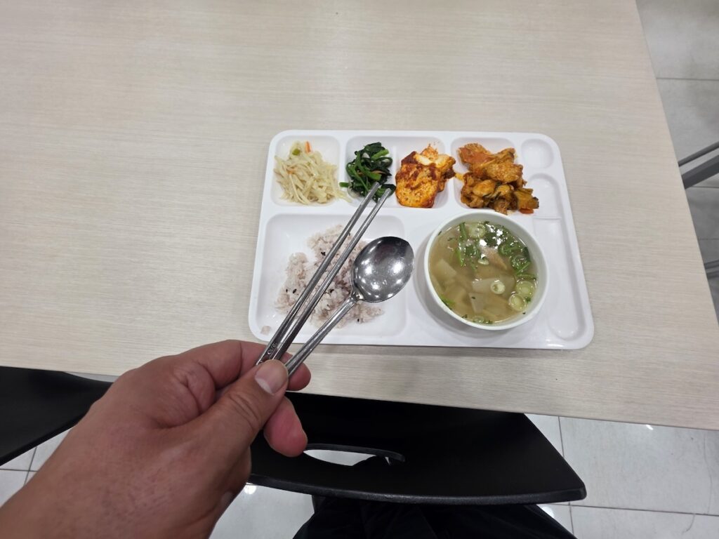 authentic-korean-geupsik-lunch-experience A first-person view of enjoying a Korean office lunch (Geupsik) with metal chopsticks and a spoon.