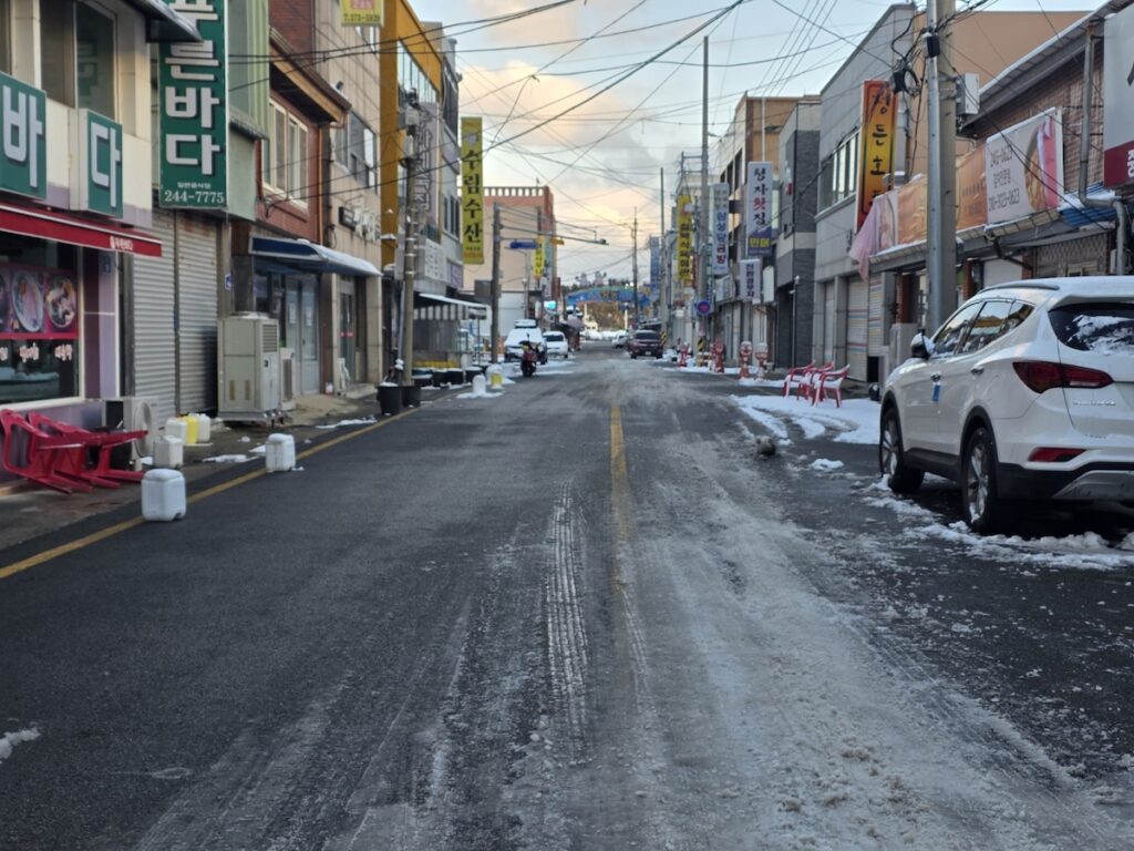 authentic-traditional-market-alley-seoul Best Places for Grocery Shopping in Seoul showing a quiet and authentic traditional market alley with snow on the ground.