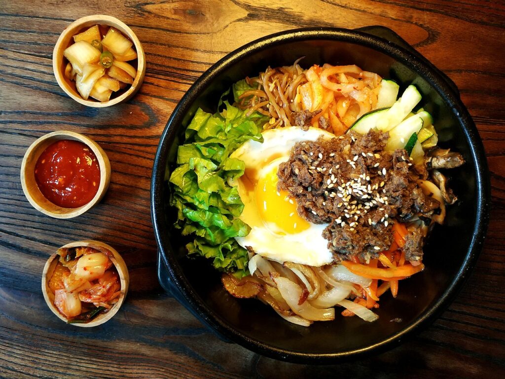 A colorful Korean bibimbap bowl topped with vegetables, rice, and a dollop of red gochujang sauce in the center.