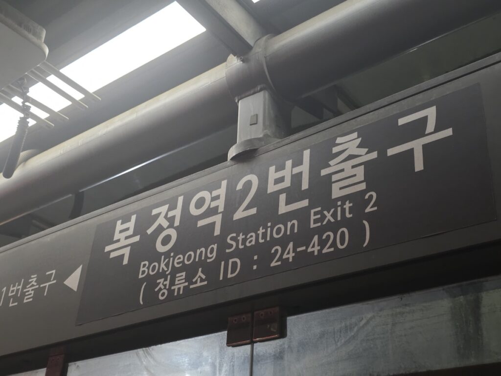 bokjeong-station-terminal-seated-commute-gangnam A dynamic night shot of the Heolleung-ro road sign showing Bokjeong Station, with a bus blurring past, illustrating the origin-point advantage for a seated commute to Gangnam.