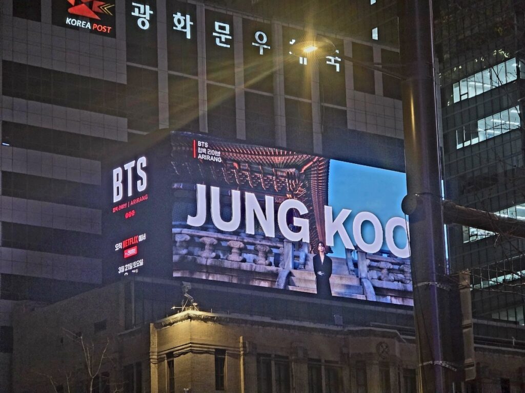 bts-gwanghwamun-comeback-2026-jungkook-billboard BTS Gwanghwamun Comeback 2026 capturing a massive digital display of BTS Jung Kook in Gwanghwamun Square, announcing a Netflix live event for ARMY fans.