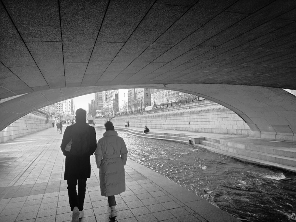 bts-gwanghwamun-locations-2026-cheonggyecheon A cinematic black and white view of the Cheonggyecheon stream, a key filming vibe for the **BTS Gwanghwamun Locations 2026**.