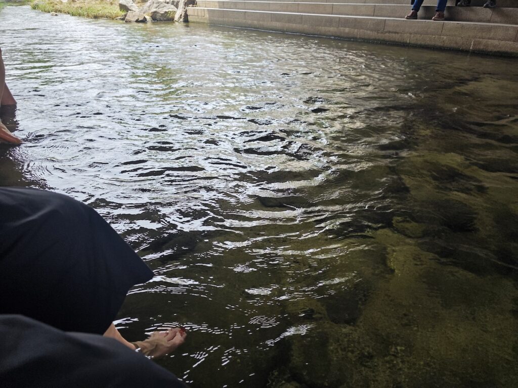 A visitor sitting beside Cheonggyecheon with feet in the water, showing a common summer scene in Seoul