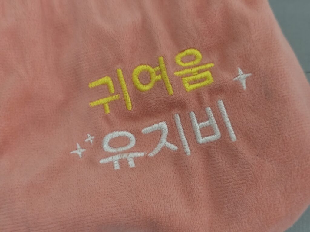 A cinematic shot of an elegantly wrapped traditional Korean gift box containing a customized Korean Hangeul towel souvenir 2026, reflecting the heritage of "Jeong."