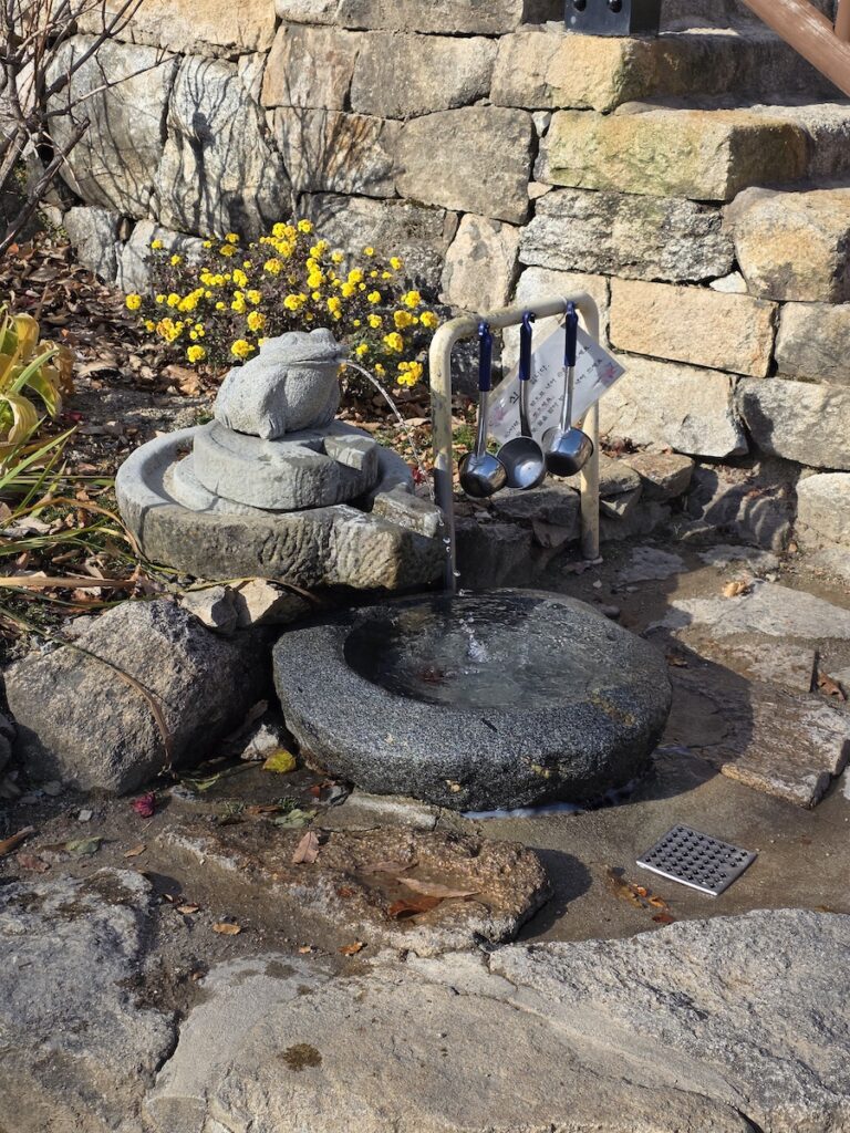 digital-detox-korea-temple-water-basin Digital detox Korea image showing a traditional temple water basin with ladles, stone walls, and quiet sunlight