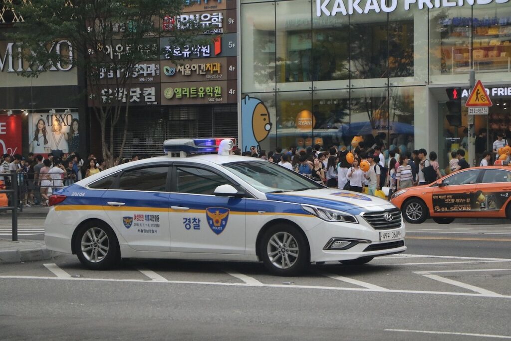 emergency-numbers-in-korea-guide-2026-police-car A South Korean police car patrolling a busy street in Gangnam, a symbol of safety in the emergency numbers in Korea guide 2026.