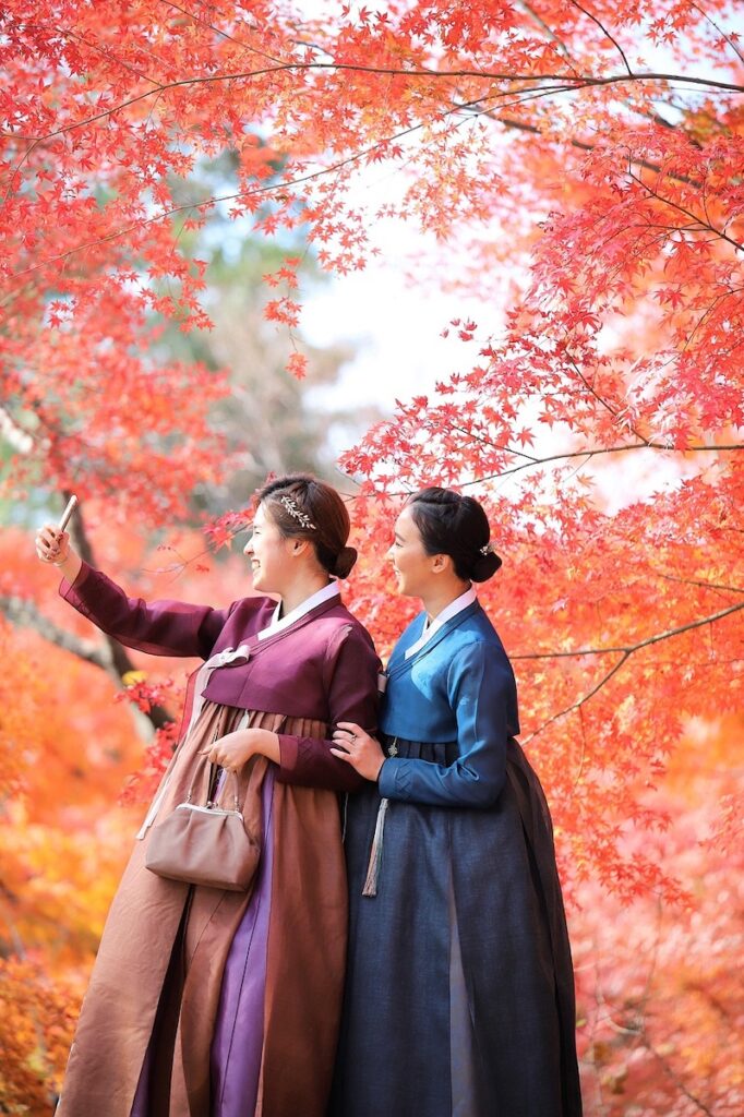 expats-enjoying-korea-with-smartphones Two women in Hanbok sharing information about the best mobile plans in Korea