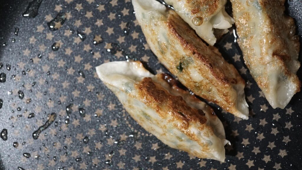 fried-dumplings-gunmandu-korea-2025 “Crispy golden fried dumplings served beside a bowl of jjambbong noodles in Seoul.”