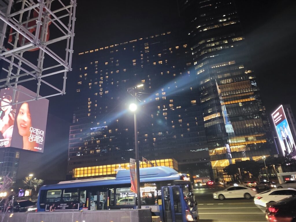 grand-intercontinental-parnas-tower-media-facade-samseong A dynamic night view of Grand InterContinental Seoul Parnas and the sleek Parnas Tower, featuring vibrant media facades and modern digital billboards next to busy city buses in Samseong-dong.