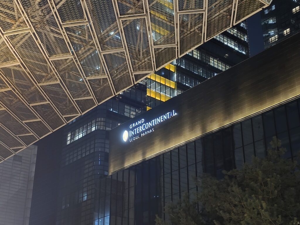 The glowing logo of Grand InterContinental Seoul Parnas on its sleek glass exterior at night, framed by the modern architectural structures of Samseong-dong, Gangnam.