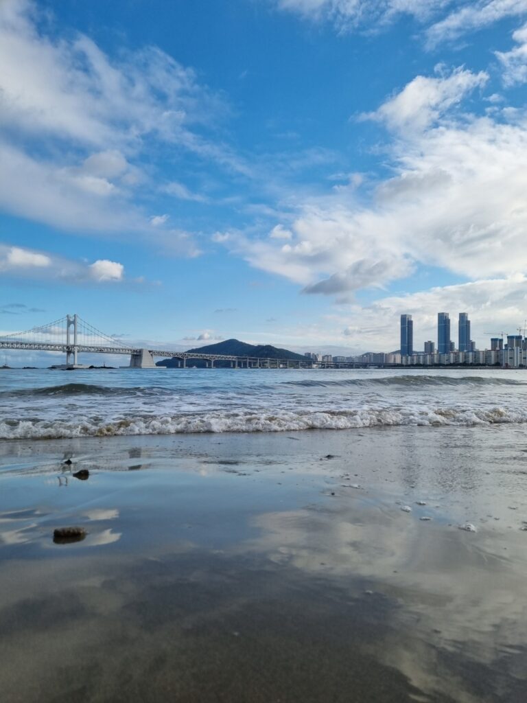 “View of Gwangan Bridge from Gwangalli Beach in Busan with people enjoying the seaside”