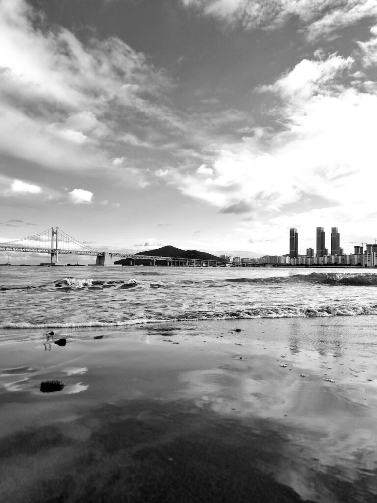 gwangalli-beach-in-busan-black-and-white A dramatic black and white landscape shot of Gwangalli Beach in Busan showing the ocean waves and the distant Gwangan Bridge.