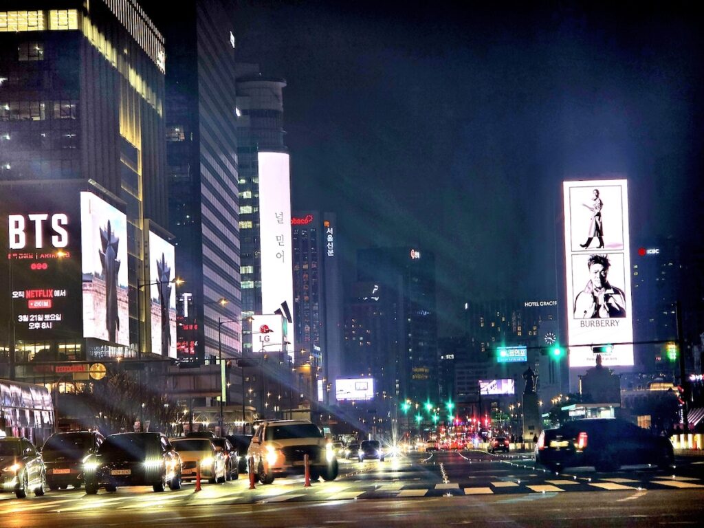 gwanghwamun-red-line-road-closure-check A wide night shot of the Sejong-daero road during a field check for the BTS Gwanghwamun Traffic Guide 2026, showing the start of the restricted vehicle zones.