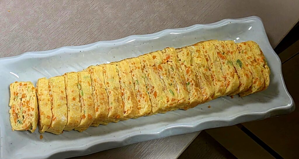 A close-up of a sliced Korean rolled omelette (Gyeran-mari) served on a plate as a banchan (side dish).
