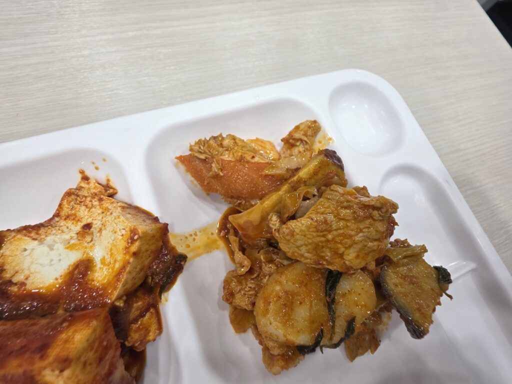 healthy-korean-office-side-dishes. Close-up of healthy Korean office lunch dishes like braised tofu and stir-fried pork.
