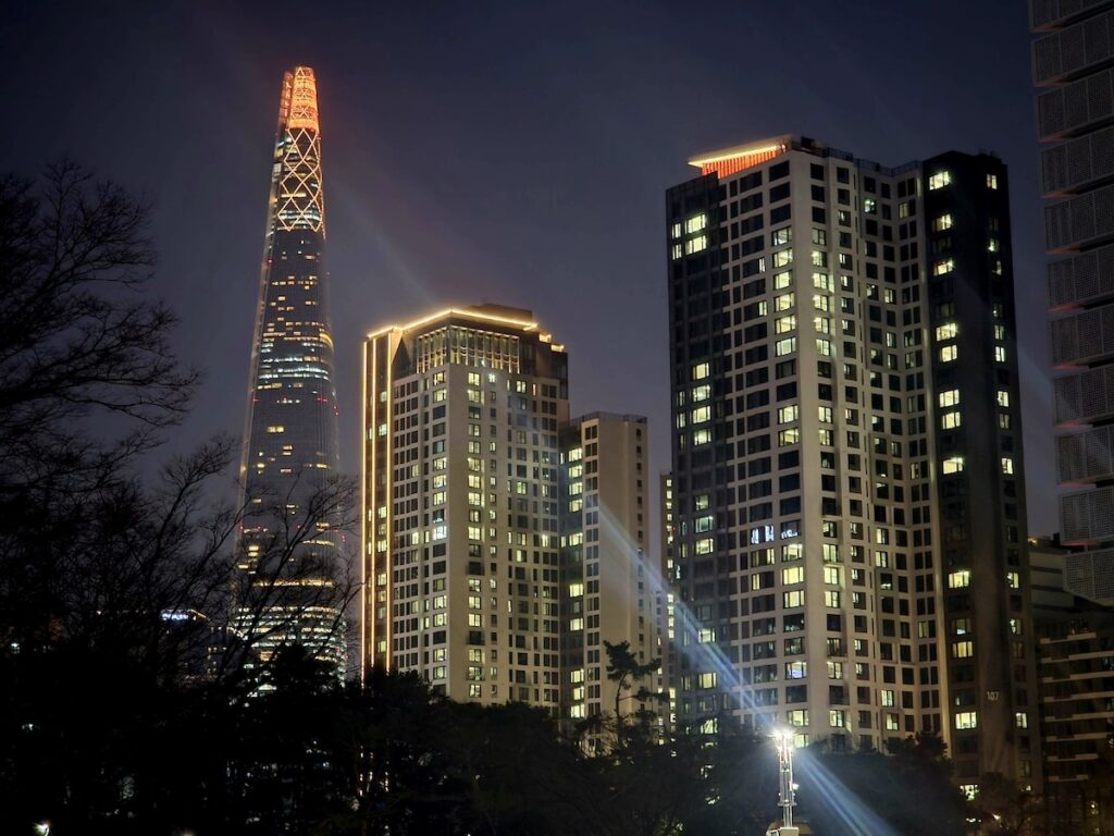 Complete 2026 guide on how to survive in Seoul as a foreigner featuring the modern night skyline and Lotte World Tower.