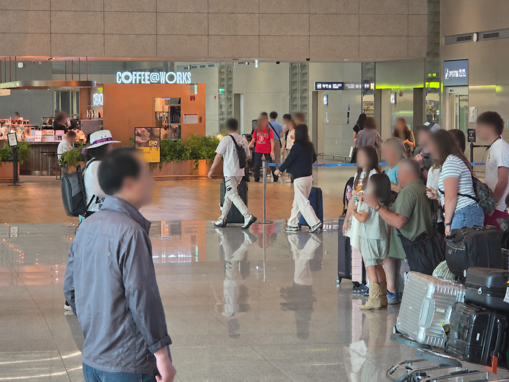 incheon-airport-arrivals-american-family-waiting American family waiting at Incheon Airport arrivals with luggage near a coffee shop
