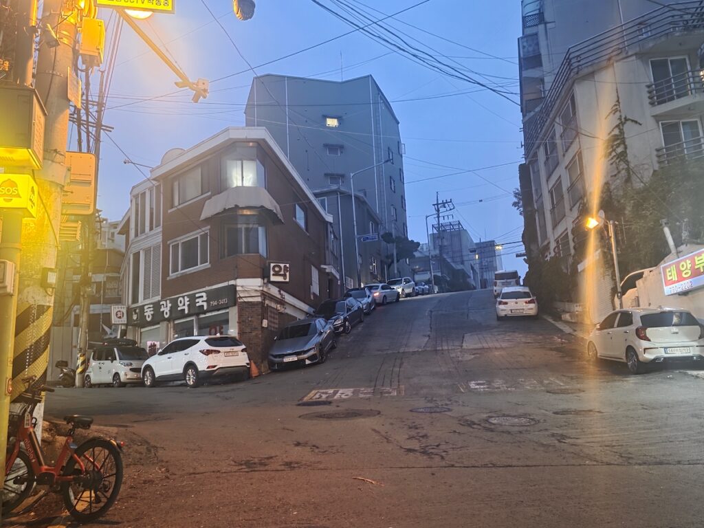 itaewon-seoul-hillside-residential-street Steep hillside residential street near Itaewon Seoul with older buildings, parked cars, and overhead wires