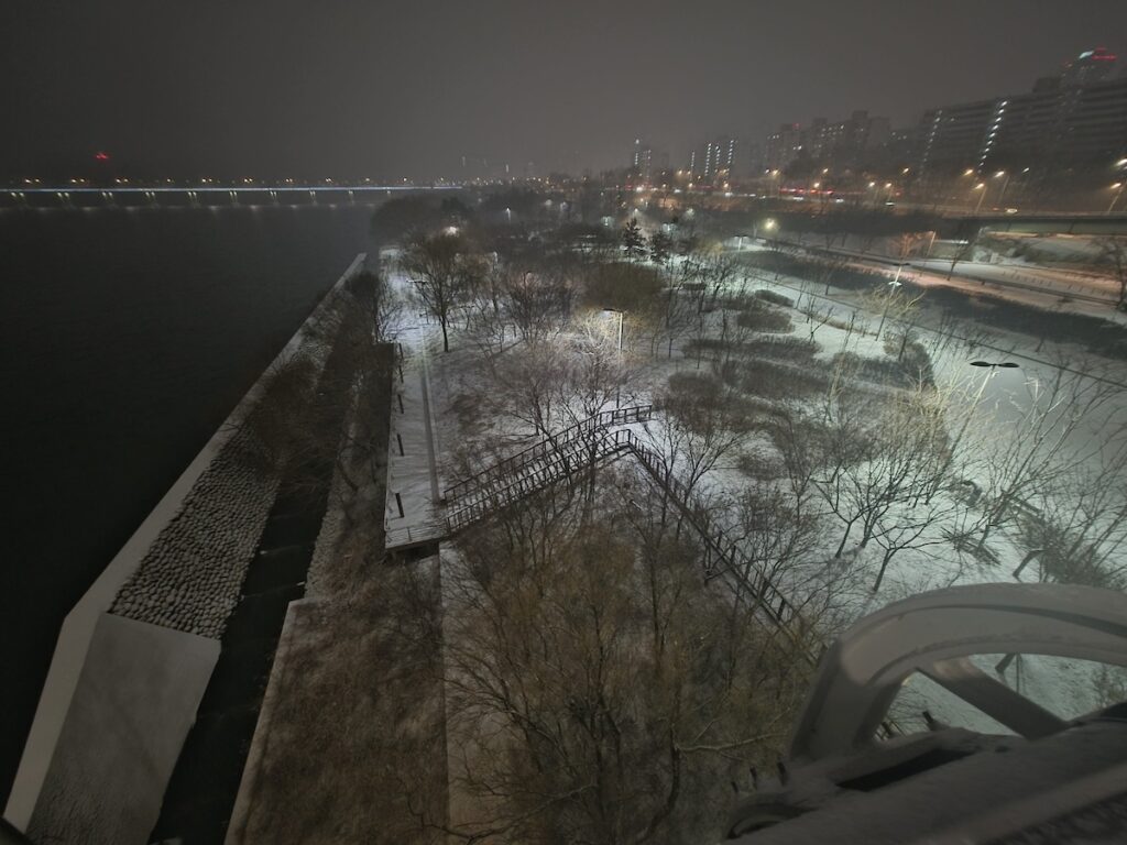 A snowy pedestrian observation deck on Jamsil Bridge in Seoul during a winter night.