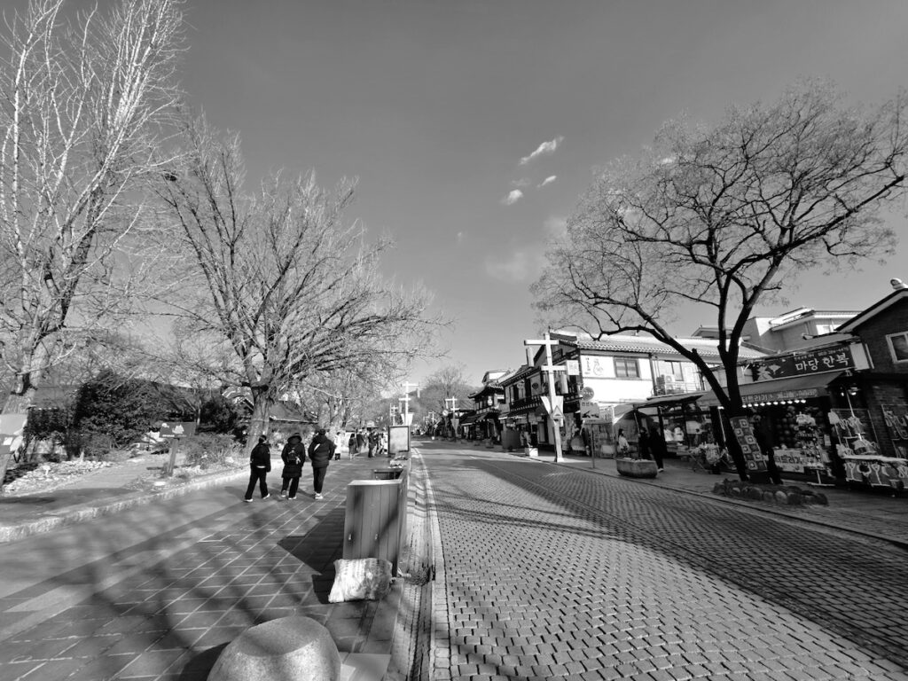 A cinematic black-and-white view of the main street during the Jeonju Hanok Village Experience, capturing the noble atmosphere.