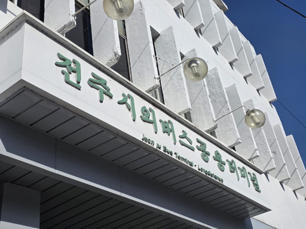 jeonju-intercity-bus-terminal-arrival-guide-2026 A close-up shot of the vintage white facade of Jeonju Intercity Bus Terminal with green Korean lettering, a key arrival point for the **Jeonju Travel Guide** 2026.