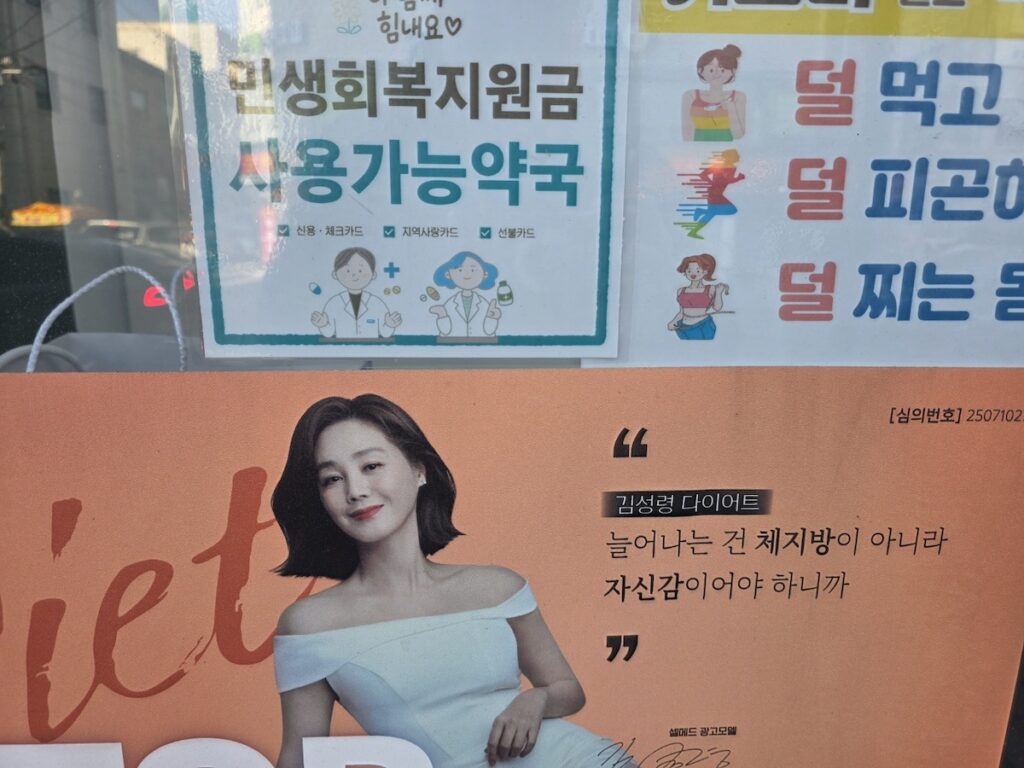 korea-pharmacy-guide-2026-health-ads Informational posters and diet ads at a Korean pharmacy entrance, reflecting the modern wellness trends in the Korea Pharmacy Guide 2026.