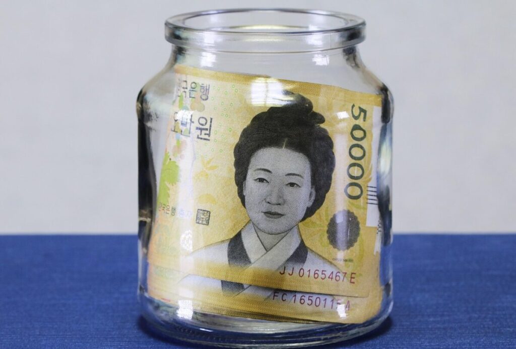 korean-bank-account-foreigners-2026-savings A glass jar filled with 50,000 KRW bills representing financial planning and a Korean bank account for foreigners in 2026.