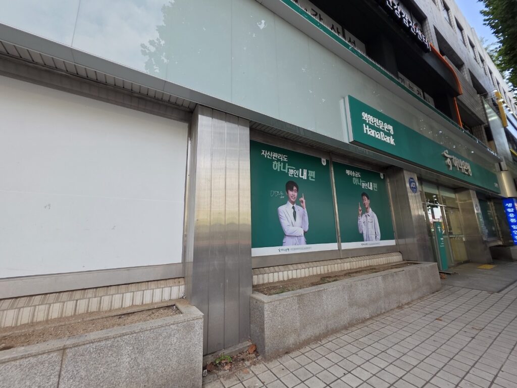 korean-bank-building-exterior “Exterior view of a modern Korean bank branch with Hana Bank and Shinhan Bank logos”