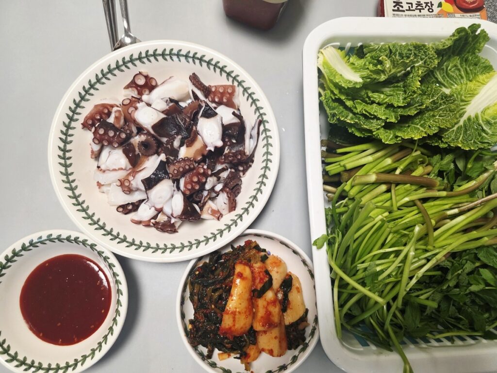 A healthy Korean table with boiled octopus, Minari, and Altari Kimchi for winter vitality.