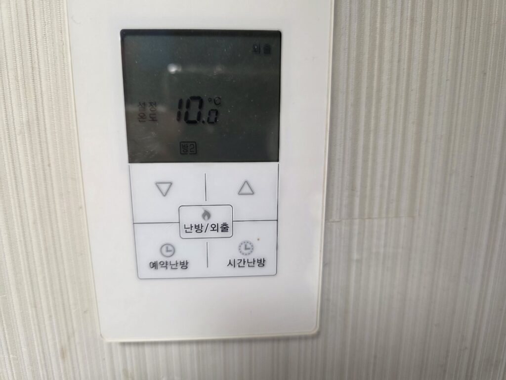 A close-up of a Korean boiler controller set to 'Away Mode' (Oe-chul), an essential feature of the heating system in South Korea to save gas.