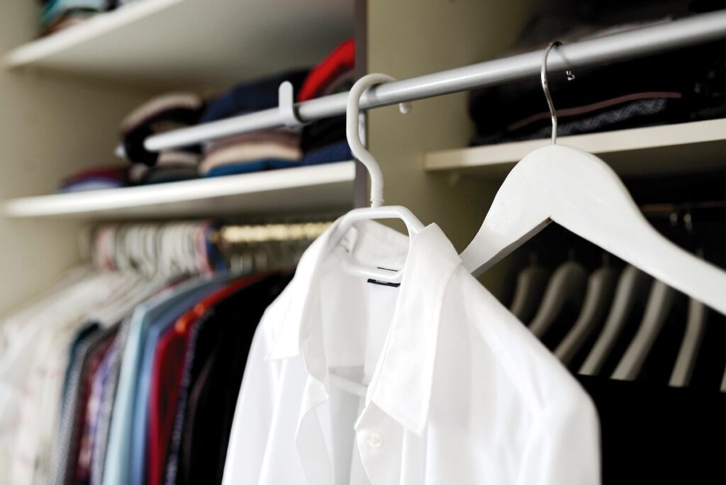 A close-up of a white collared shirt on a hanger in a Korean fashion store, illustrating the sleeve length and fit challenges discussed in the Korean clothing size guide.