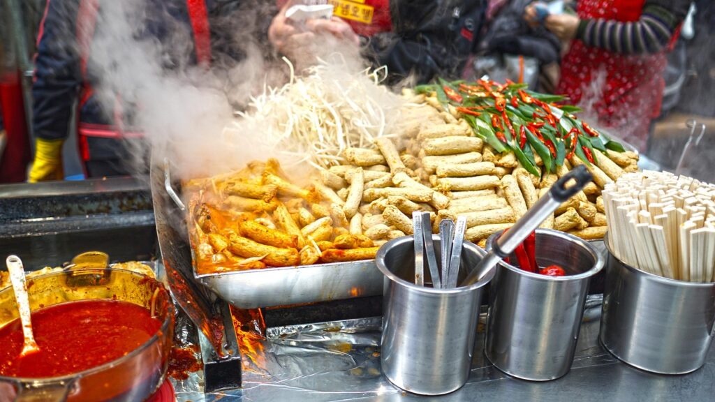 “Korean street food stall serving fish cakes (eomuk) and spicy rice cakes (tteokbokki), a popular combination among locals during chilly seasons.”