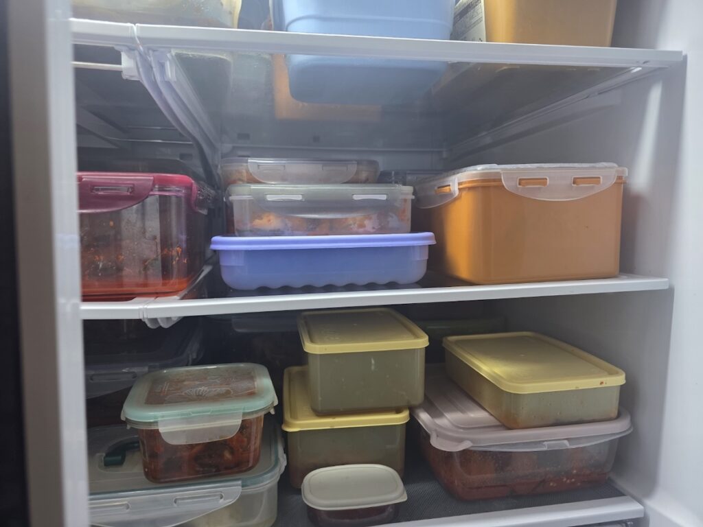 korean-fridge-organization-meal-prep A well-organized Korean refrigerator showing various banchan stored in airtight containers for efficient meal prep.
