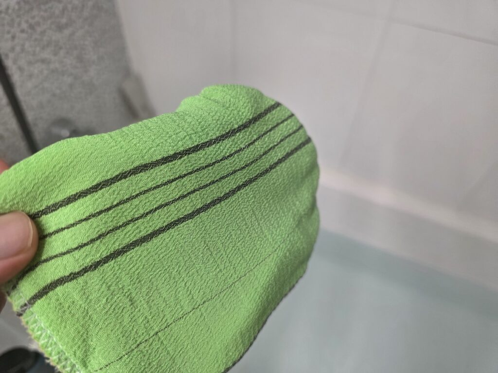A classic green Korean exfoliating mitt (Italy Towel) with black stripes, used for standard body scrubbing.