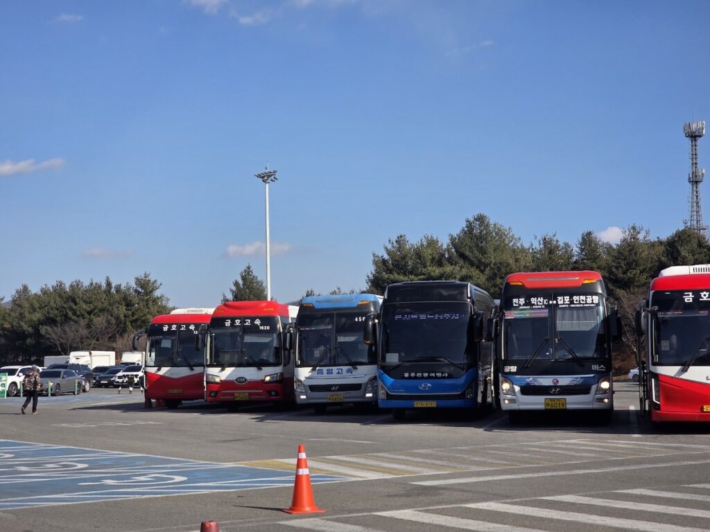 korean-highway-rest-area-bus-parking-lot Rows of identical red express buses at a Korean Highway Rest Area, illustrating why travelers must remember their bus location.