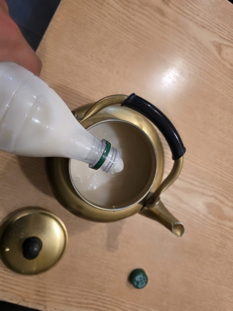 Pouring Korean rice wine from a yellow kettle, representing the continuity of Korean Makgeolli culture.