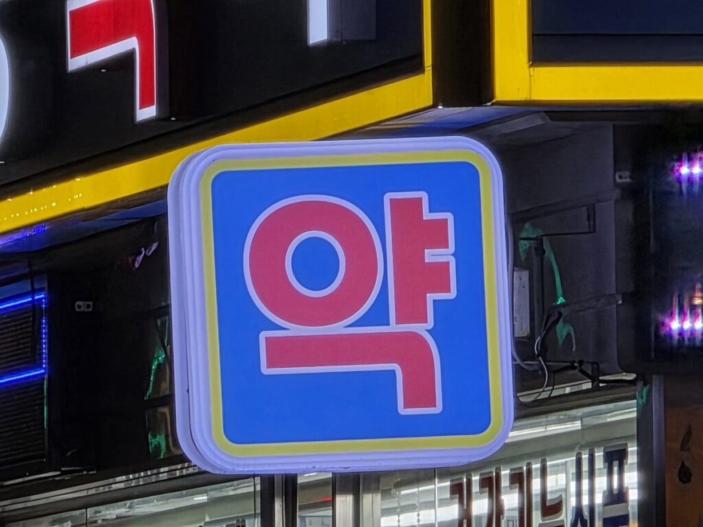 korean-pharmacy-red-sign-jongno-5-ga A close-up of a bold red "YAK" (Pharmacy) sign on a blue background at Jongno 5-ga Pharmacy Street, symbolizing the heart of Korean pharmaceutical commerce.