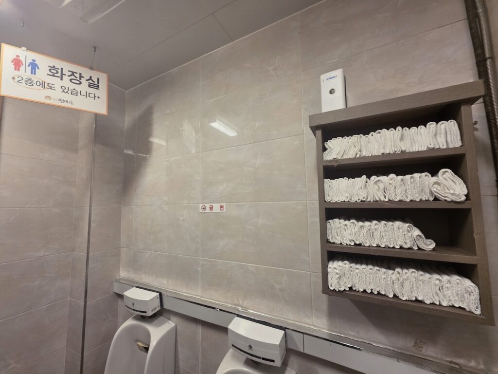 korean-restaurant-bathrooms-individual-towels A wooden rack filled with neatly rolled individual cotton towels in Korean restaurant bathrooms, showcasing local hospitality.