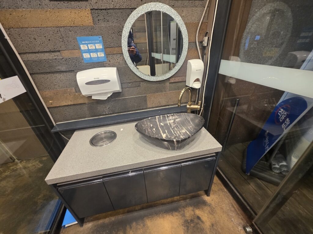 korean-restaurant-bathrooms-premium-sink A stylish stone basin with a gold faucet and hand wash station in premium Korean restaurant bathrooms.