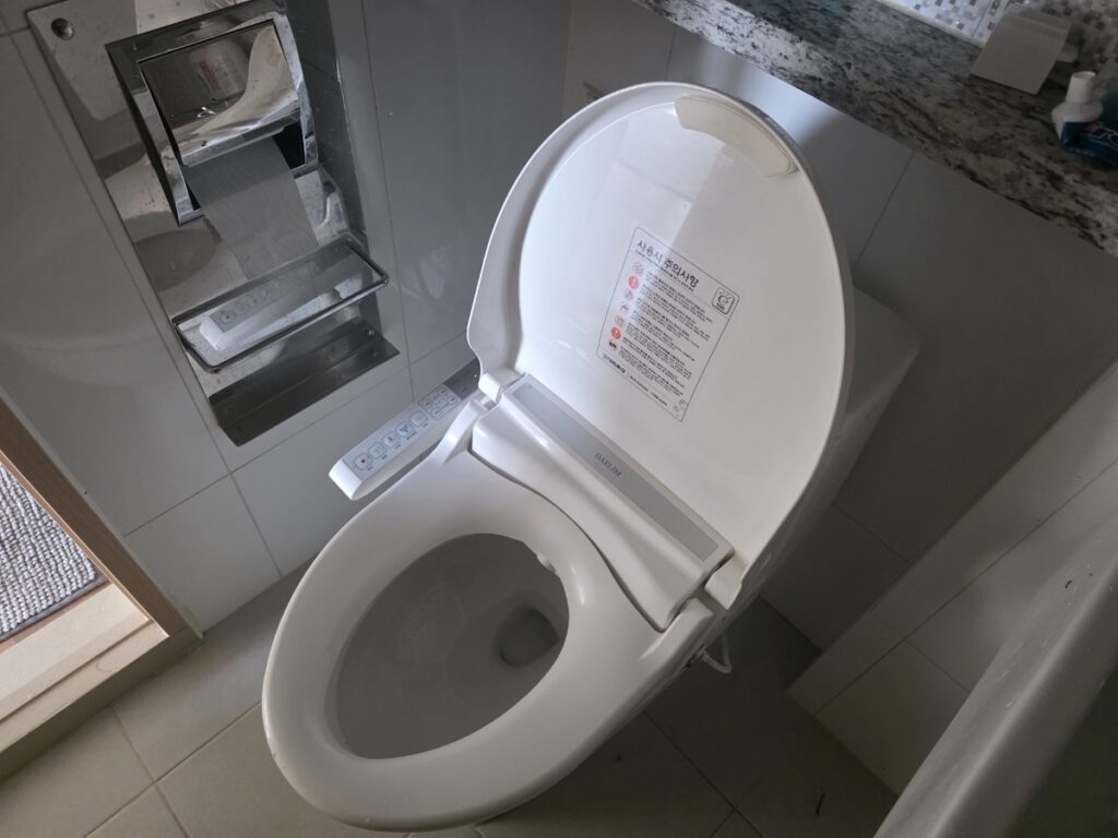 A modern white toilet equipped with a high-tech smart bidet in a Korean home bathroom.