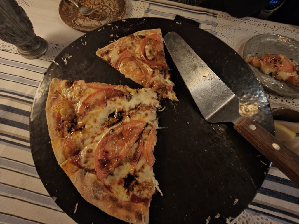 korean-style-pizza-with-fresh-toppings A delicious slice of Korean-style pizza with tomato and meat toppings, served on a black wooden board.