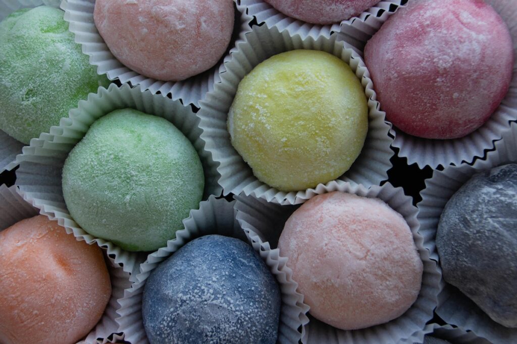 “Assorted Korean rice cakes (tteok) including injeolmi, songpyeon, and baekseolgi on a wooden plate”