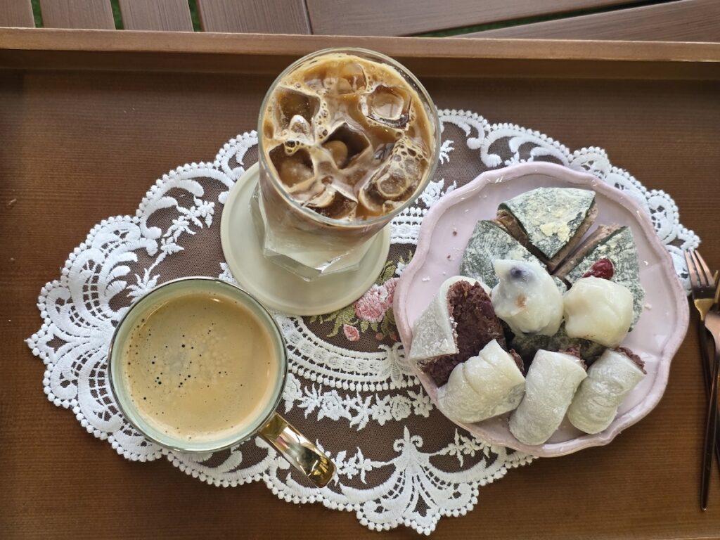 A sophisticated pairing of traditional Korean rice cakes and iced coffee on a lace doily, a highlight of the Korean tteok rice cake guide 2026.
