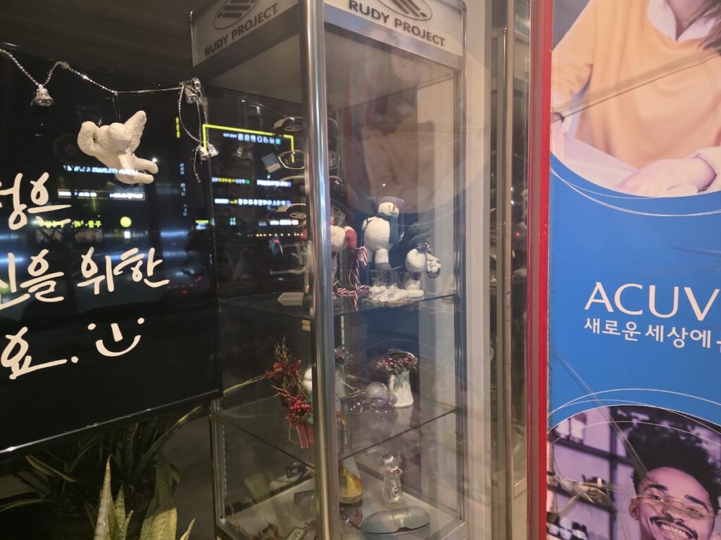 kpop-idol-inspired-eyewear-store-korea The entrance of a Korean eyewear store with K-pop idol-style contact lens posters and a warm, welcoming interior.