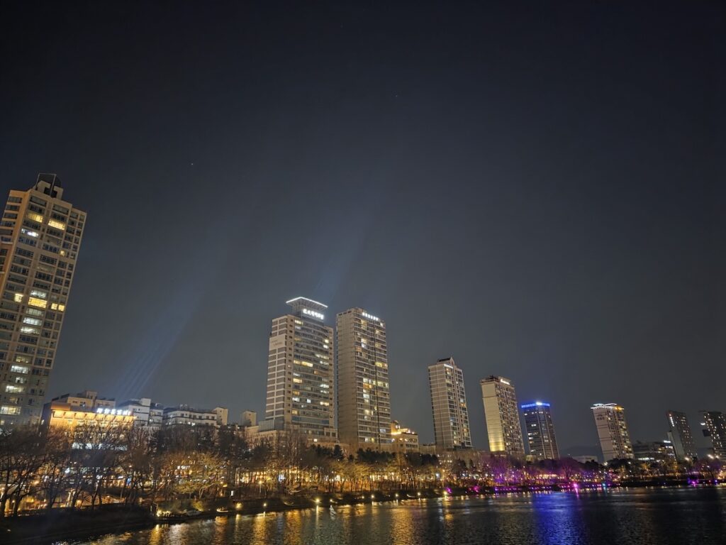 High-rise apartment complexes in Seoul reflected in the water at night, representing the inaccessible housing market and rental challenges for expats during their Life in Korea Without ARC.