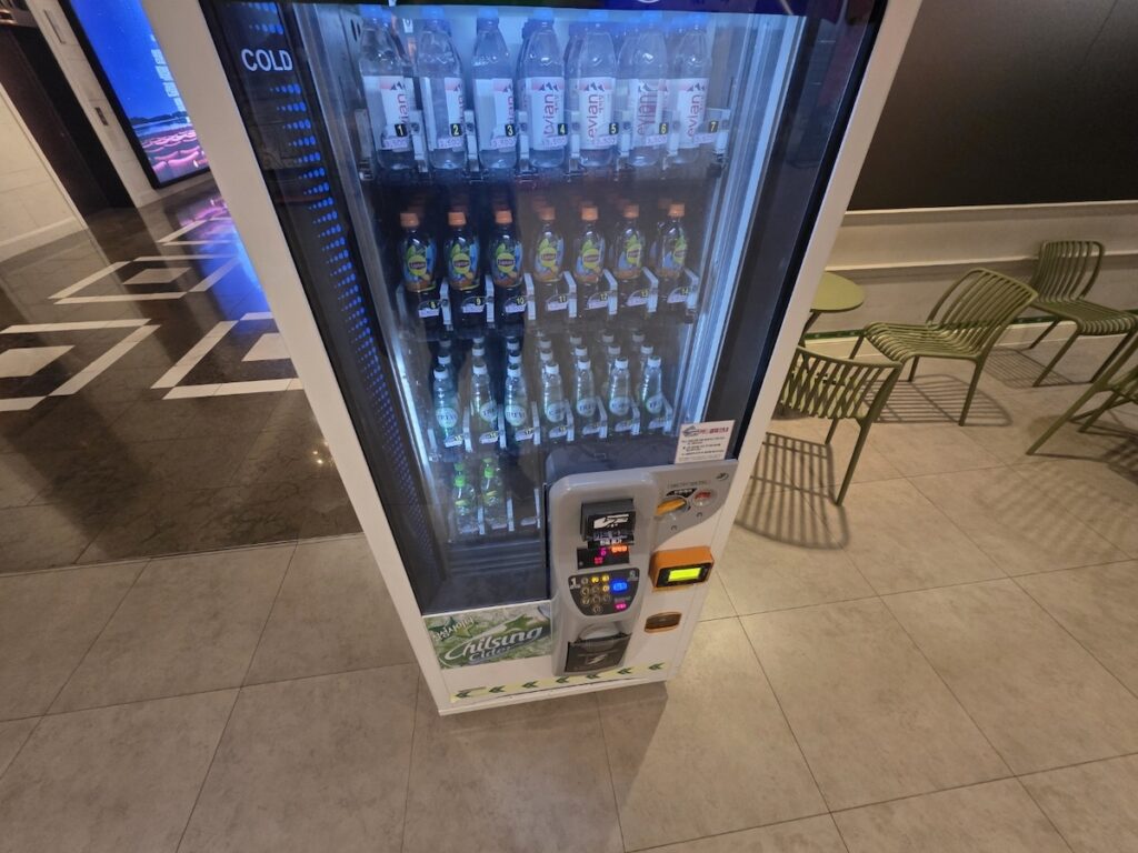 lotte-cinema-jamsil-vending-machine-snacks-drinks A specialized vending machine at Lotte Cinema Jamsil offering unique Korean snacks and Evian water to compare prices with standard movie theater offerings.