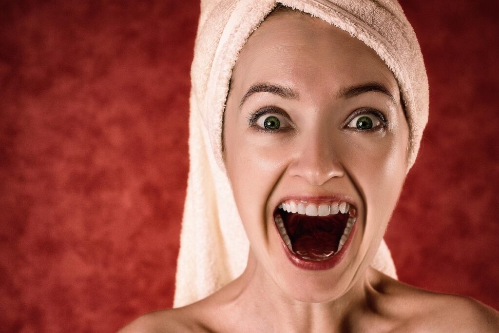 A woman with a towel on her head expressing joy after a revitalizing facial treatment, representing the restorative results of Luxury Korea Travel.